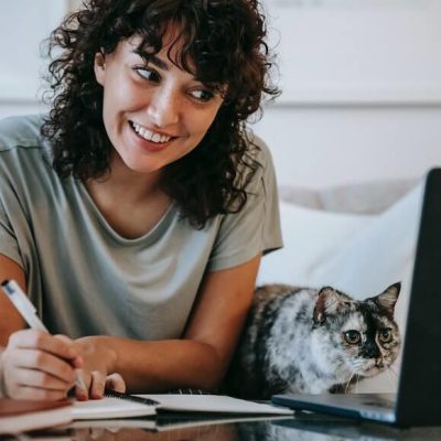 woman working on her laptop in company of her cat